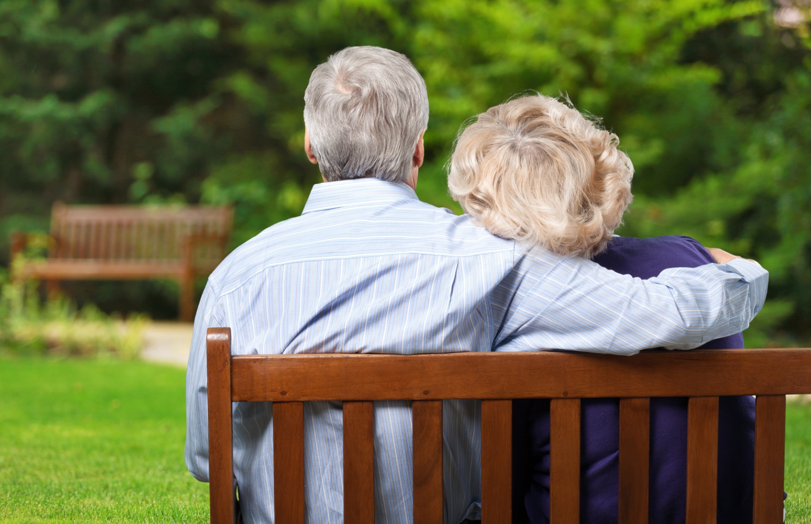 A couple of people sitting on top of a wooden bench.