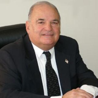 A man in suit and tie sitting at a desk.